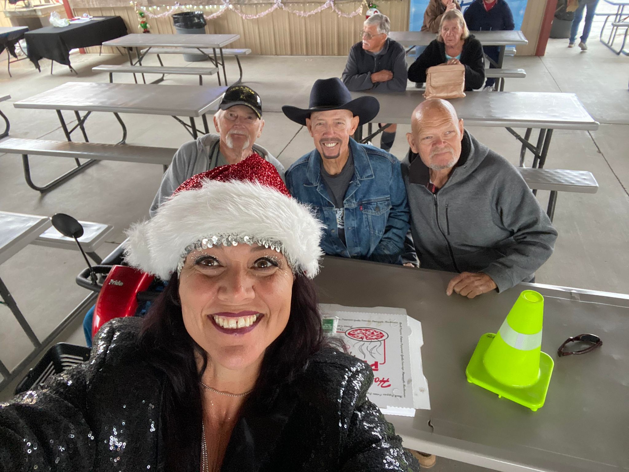 Kat taking a holiday selfie with three men seated behind her.