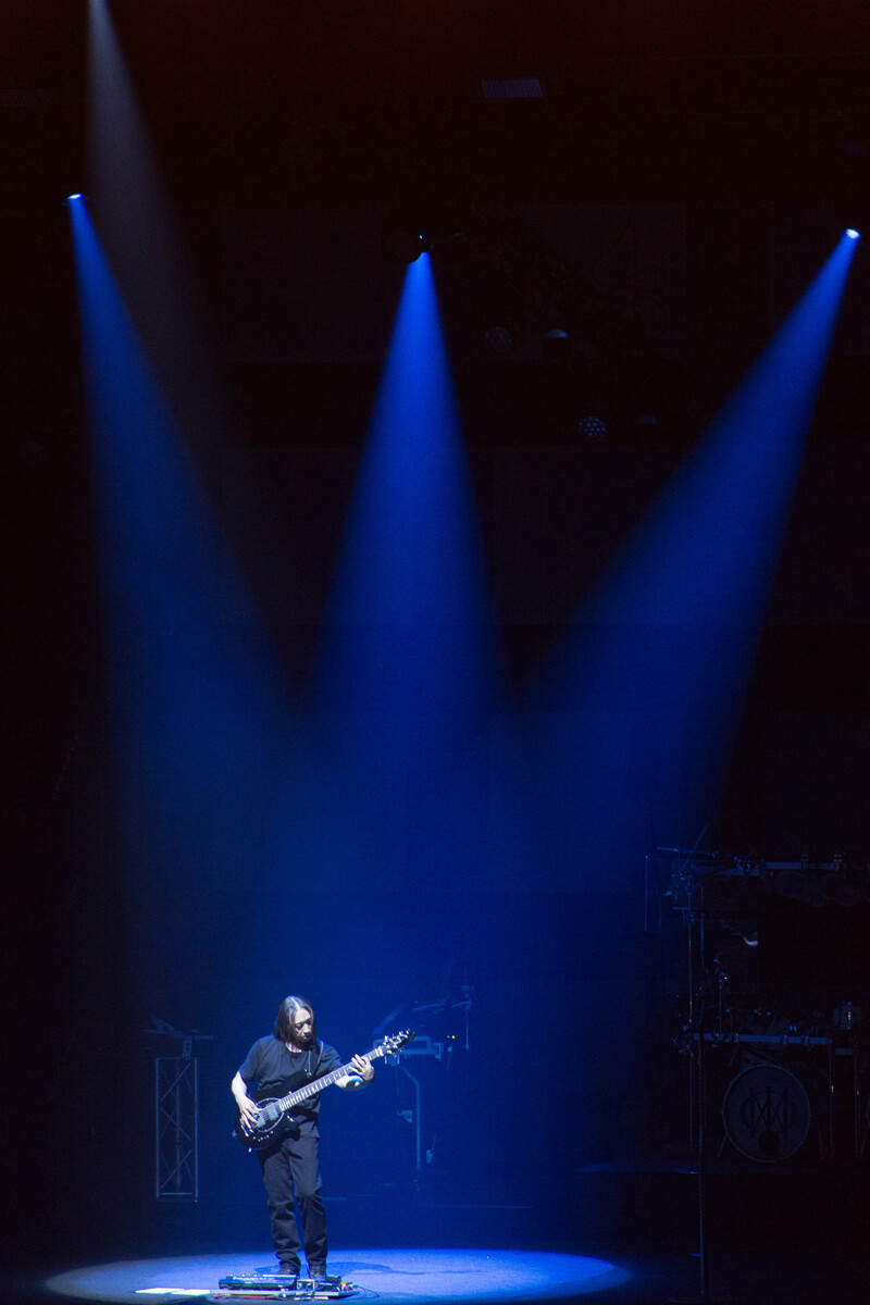 Picture of bass player John Myung on stage doing a solo