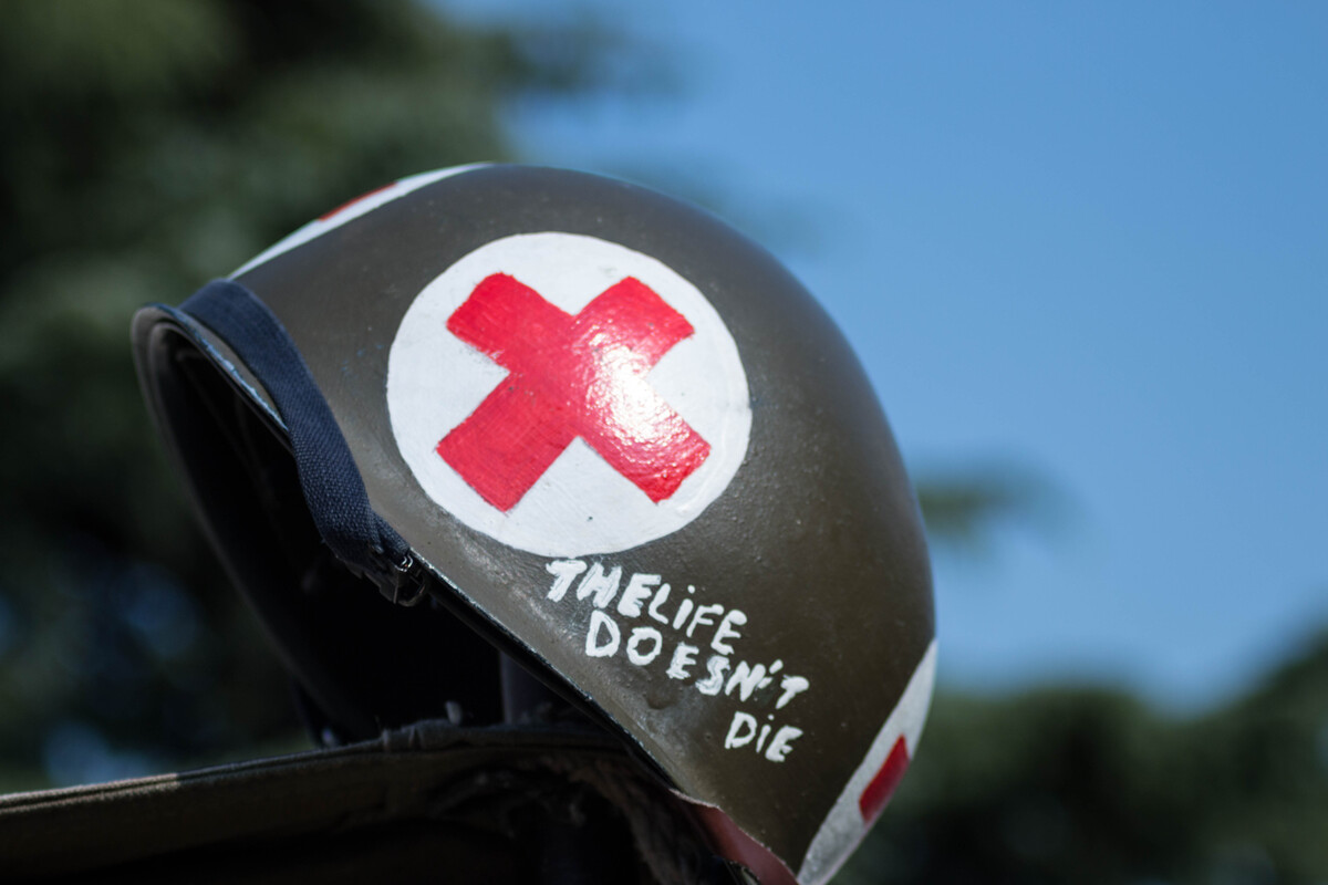 A helmet with a red cross painting and a message with written "The life doesn't die"
