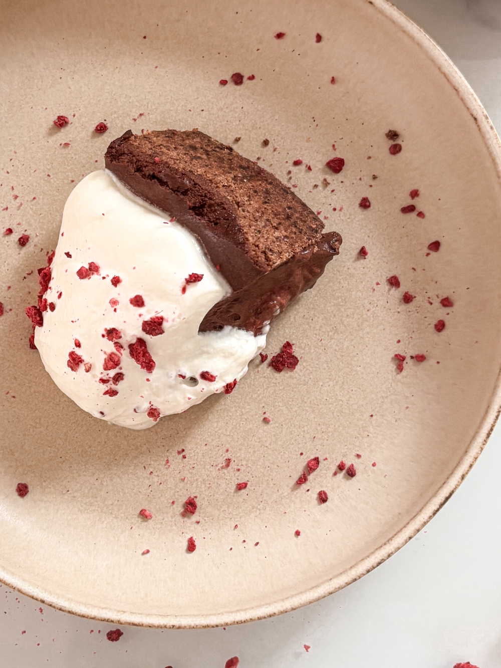 Čokoladna mousse torta z malinovim nadevom - Chocolate mousse cake with raspberry filling and whipped cream on a beige plate 