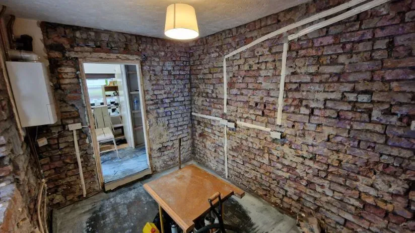 Wide renovation view of a kitchen with a wall-mounted boiler and all brick walls stripped back for professional damp proofing treatment in Totterdown, Bristol.