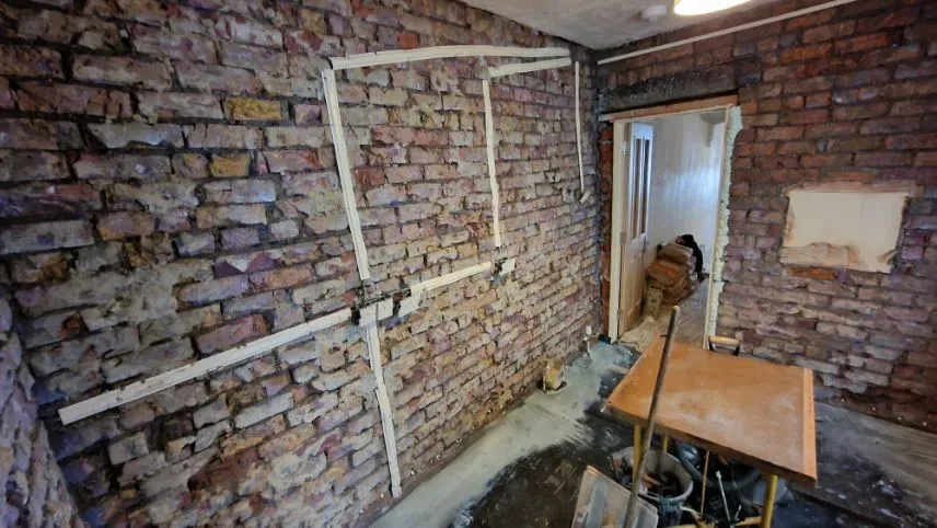 Internal kitchen wall stripped down to bare brickwork with damp proof course preparation and tracking visible during a renovation in Totterdown, Bristol.