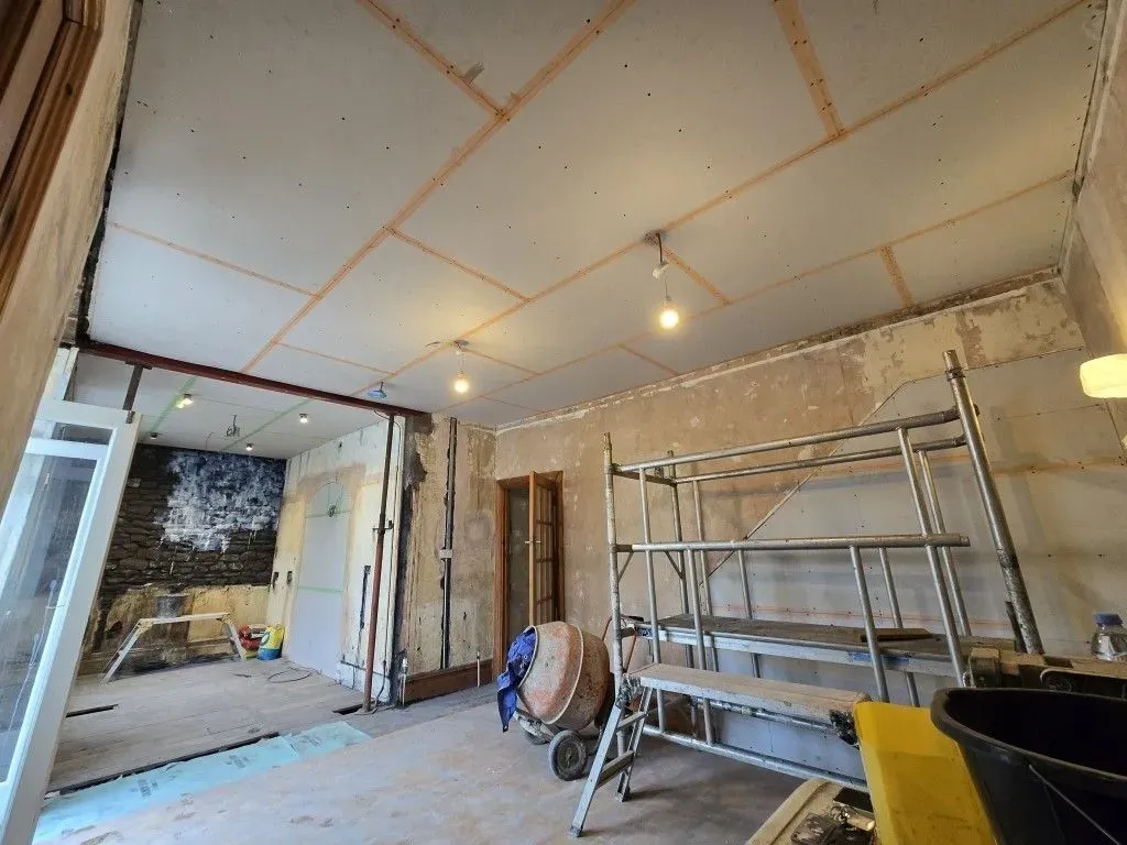 Plastering preparation in a Redland home renovation, highlighting structural support, new ceiling boards, and site setup including a cement mixer.