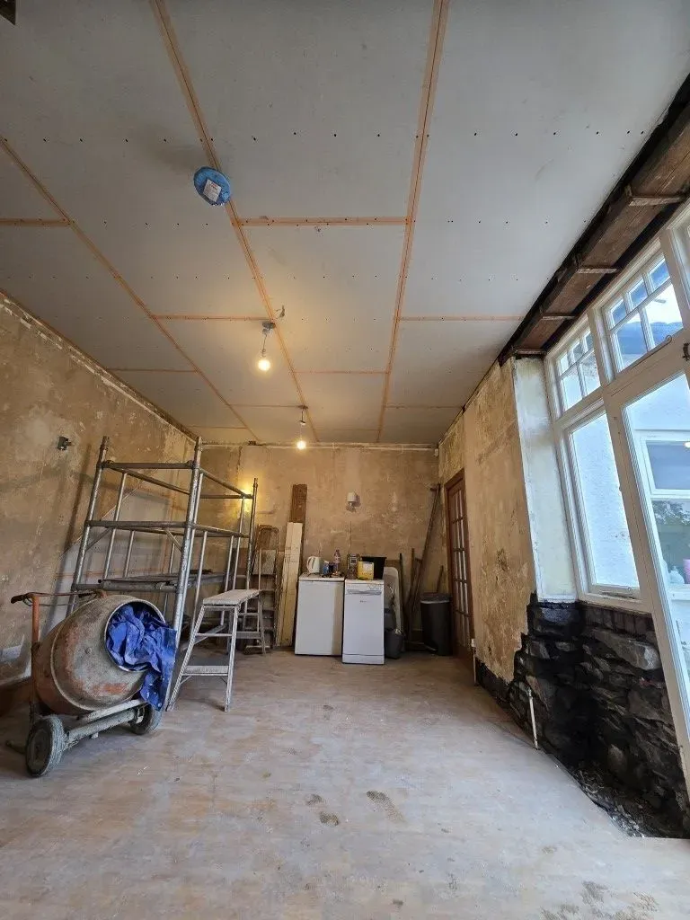Plastering preparation in a Redland home renovation, highlighting structural support, new ceiling boards, and site setup including a cement mixer.