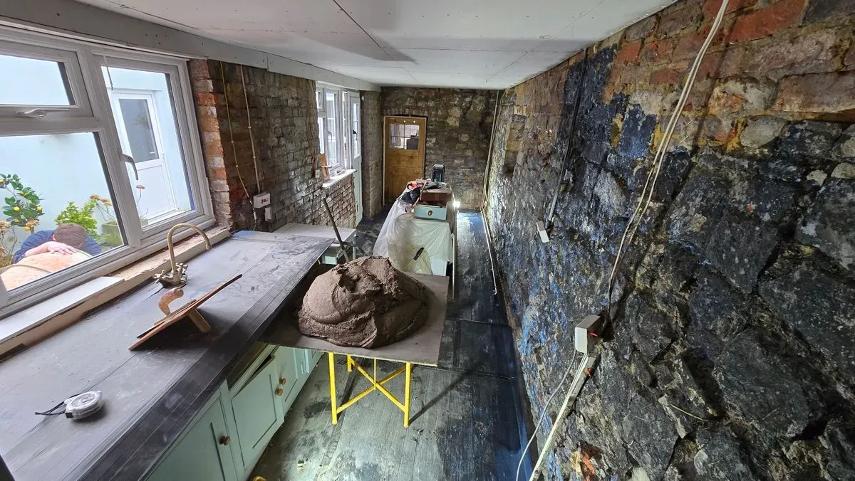 Structural waterproofing and damp proofing tanking slurry applied to an exposed stone wall in an old cottage kitchen renovation in Bristol.