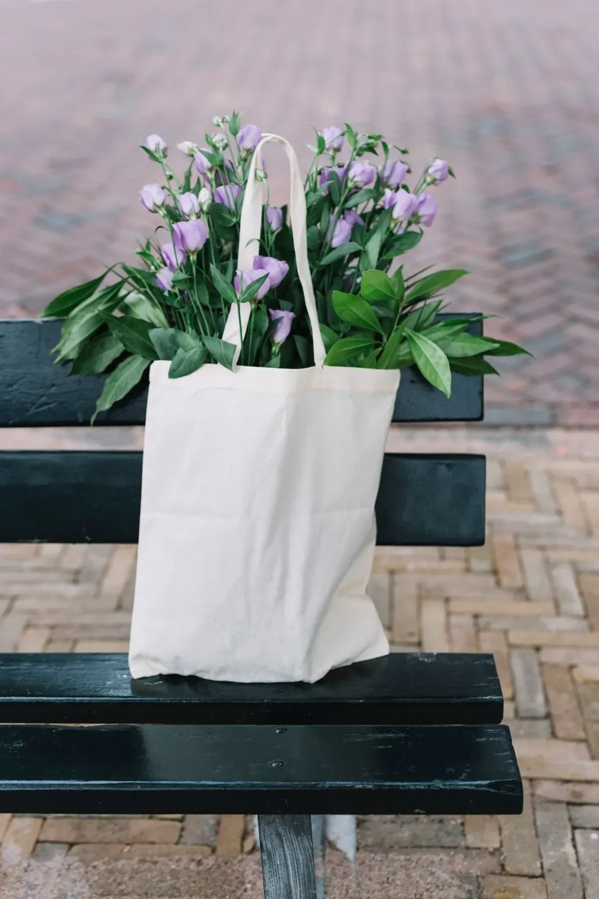 white-cotton-handbag-with-beautiful-purple-eustoma-flowers-black-bench thumbnail image