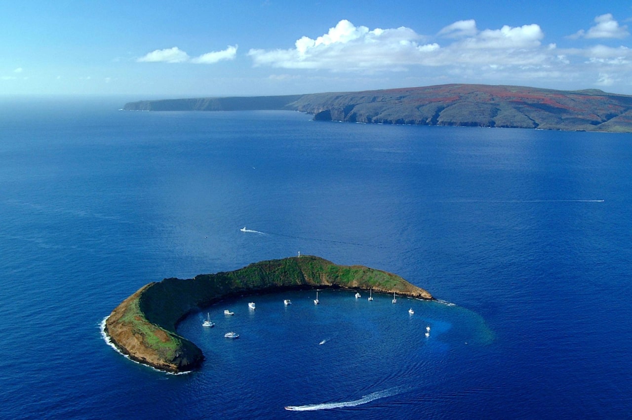 Molokini islet off of the Maui, Hawaii coast with snorkeling boats anchored.