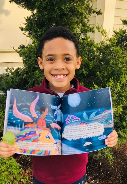 Boy holding book open on blue sea pages