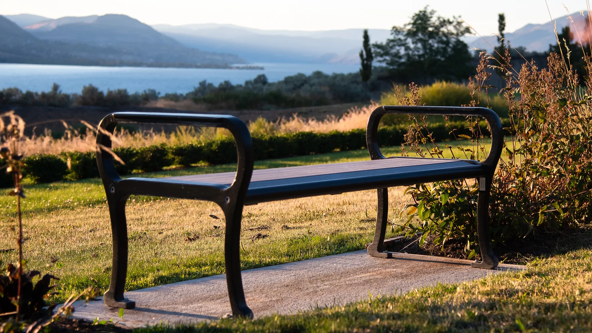 A Mountain Classic bench offers a place to rest and enjoy the view of Okanagan Lake. The bench features recycled plastic lumber and a black powder-coated frame.