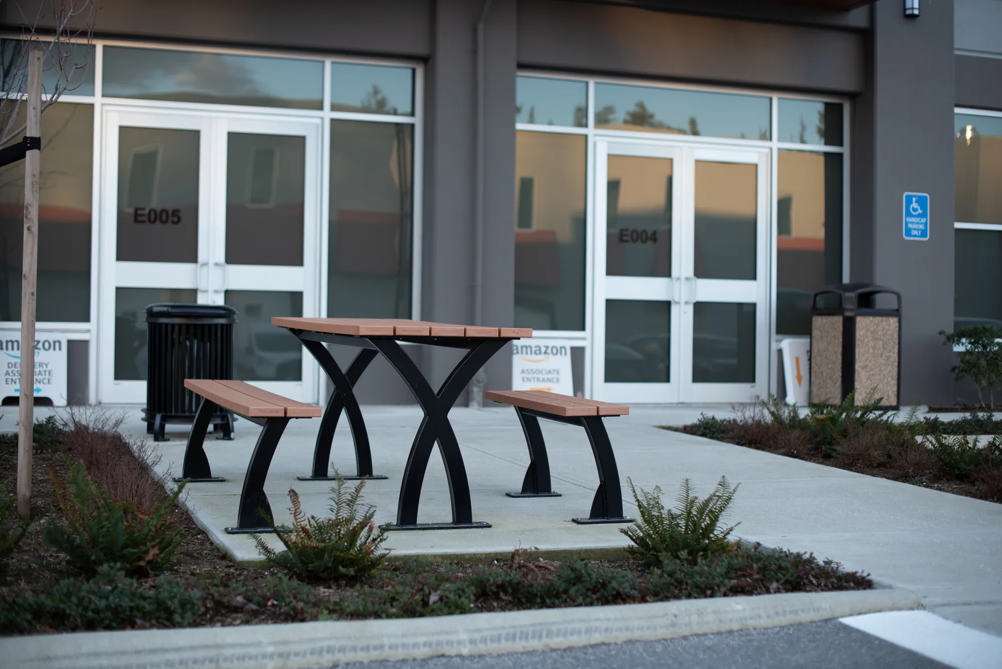 Parker Picnic Table with benches provides an outdoor seating area for Amazon associates. The table features recycled plastic lumber and a black powder-coated frame.