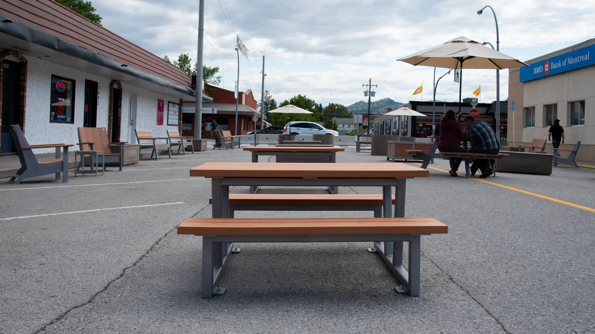 Outdoor picnic tables and lounge seating create a welcoming streetscape in Osoyoos, British Columbia. The site furniture offers a place for people to gather and relax.