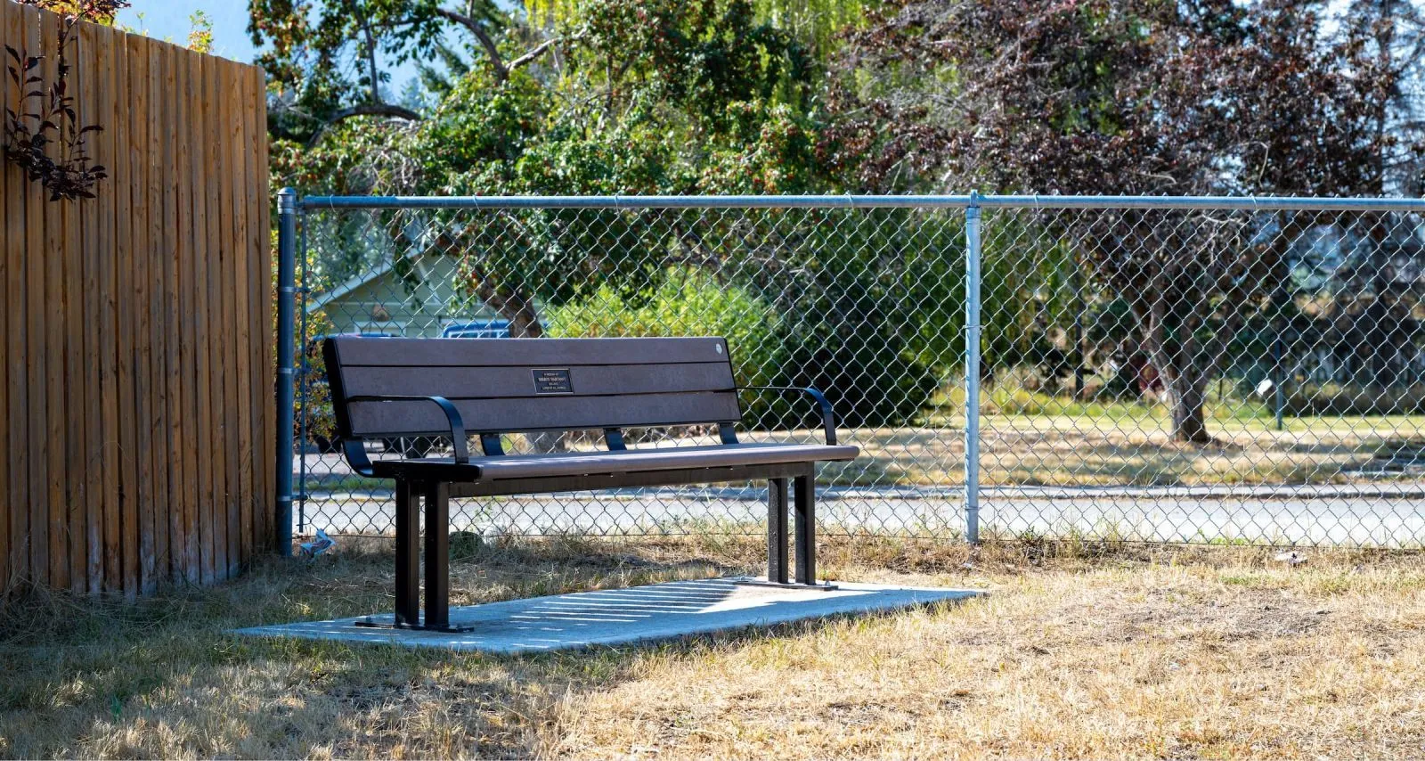 Larson memorial bench in a park setting. The bench features recycled plastic lumber and a black powder-coated frame.