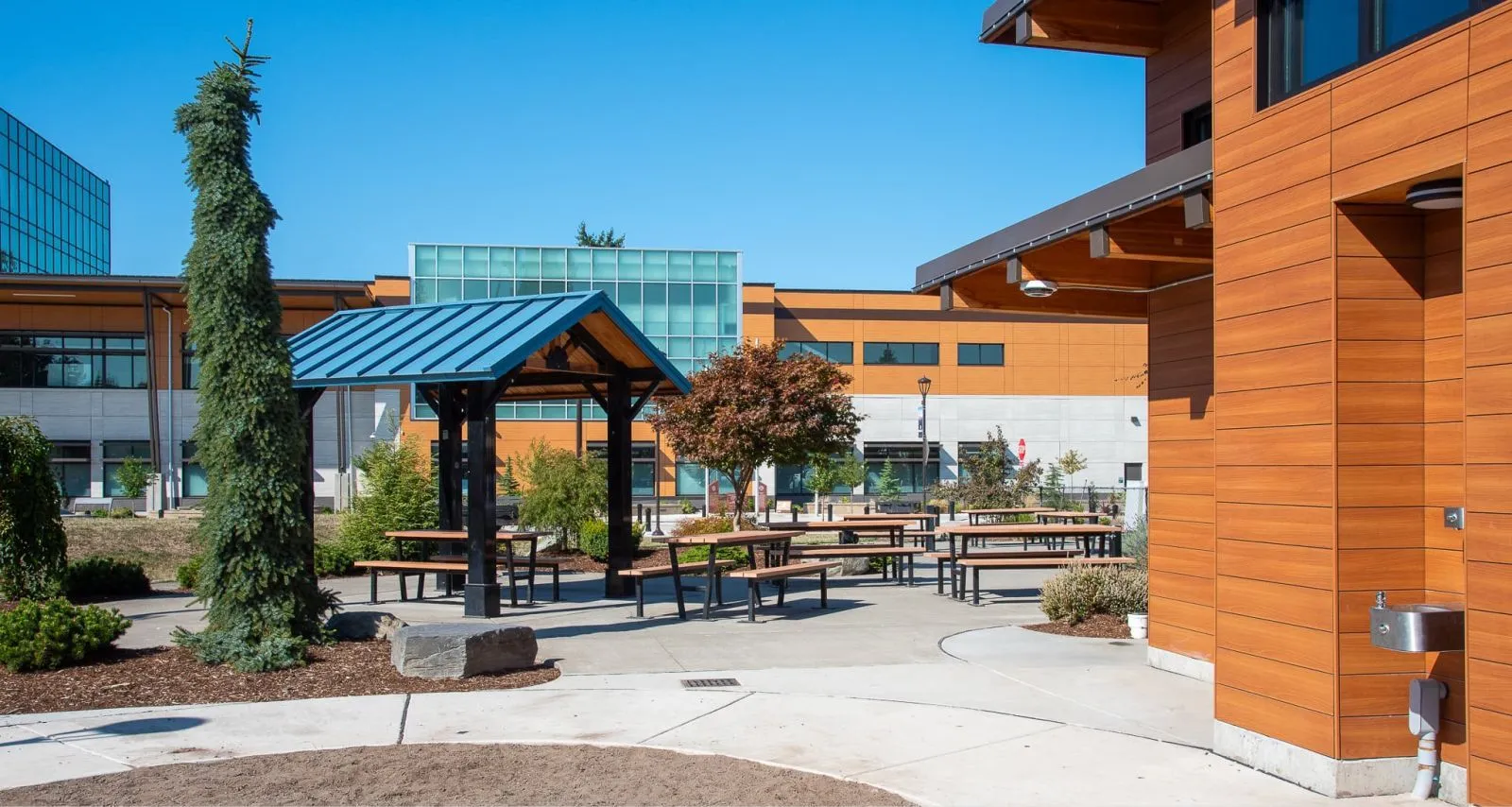 Outdoor picnic tables offer a place to relax and gather at Comeford Park in Marysville, Washington. The tables feature recycled plastic lumber and a black powder-coated metal frame.