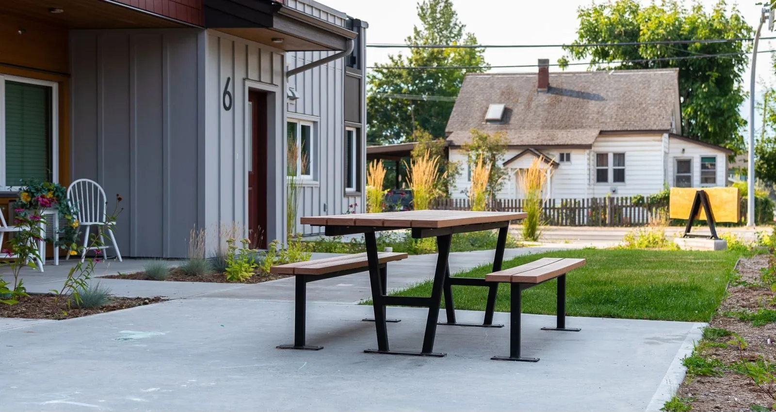 Wheelchair-accessible picnic table provides an inclusive outdoor dining space. The table features a durable recycled plastic lumber top and benches with a sturdy black powder-coated metal frame.