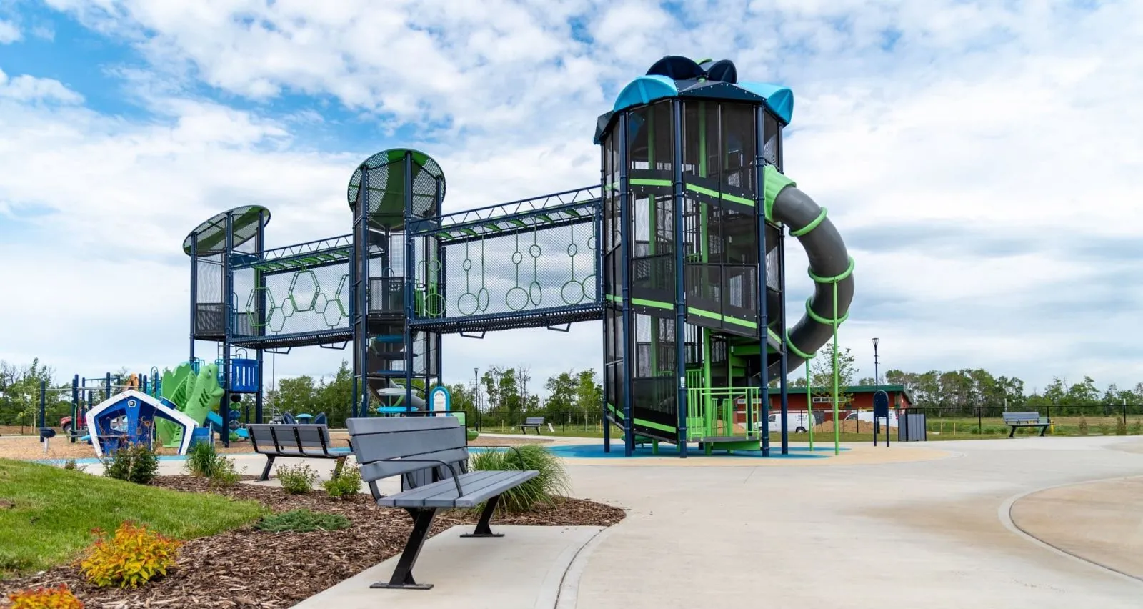 Bayview benches offer seating near a modern playground structure. This park provides a recreational space for the community.