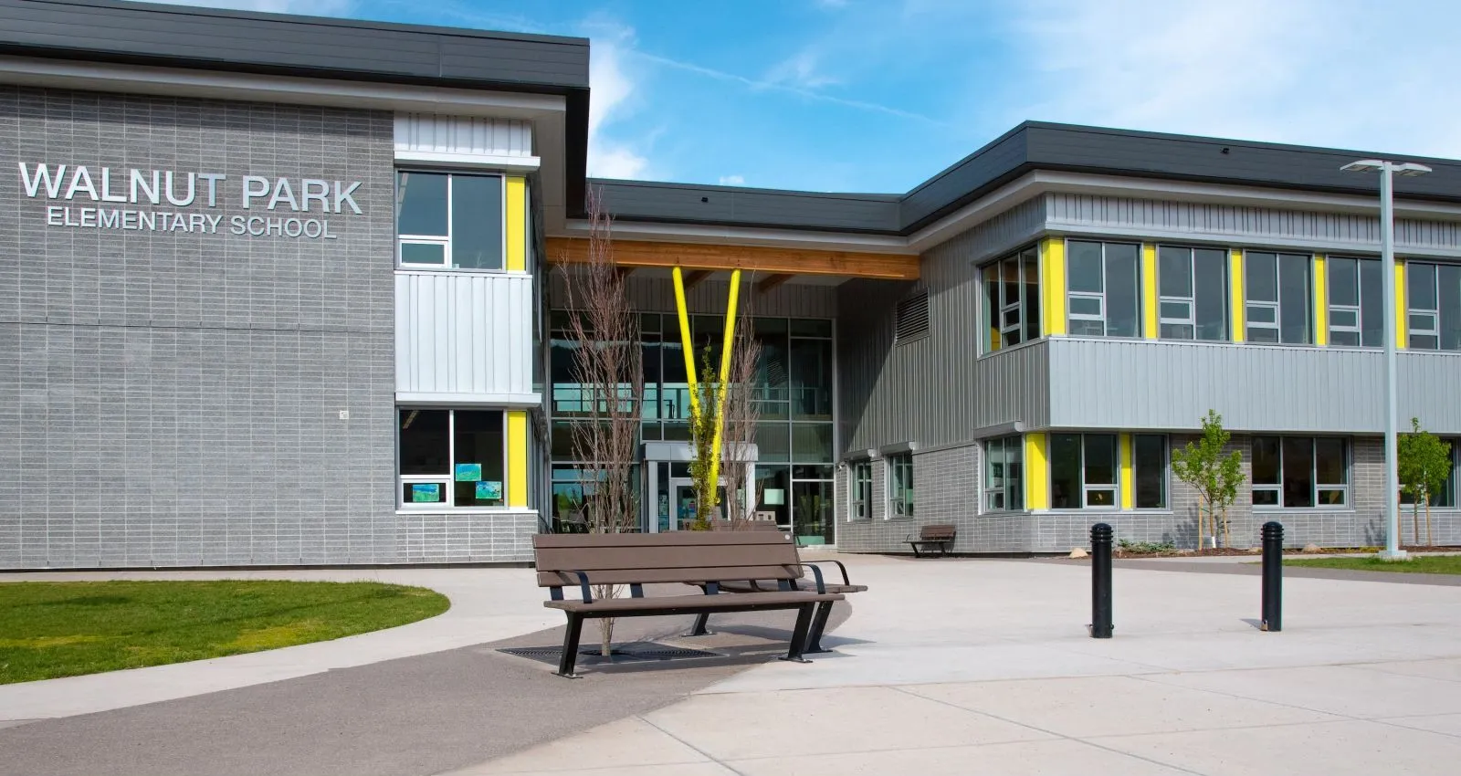 A Bayview bench sits outside Walnut Park Elementary School. The bench features recycled plastic lumber and a black powder-coated frame.