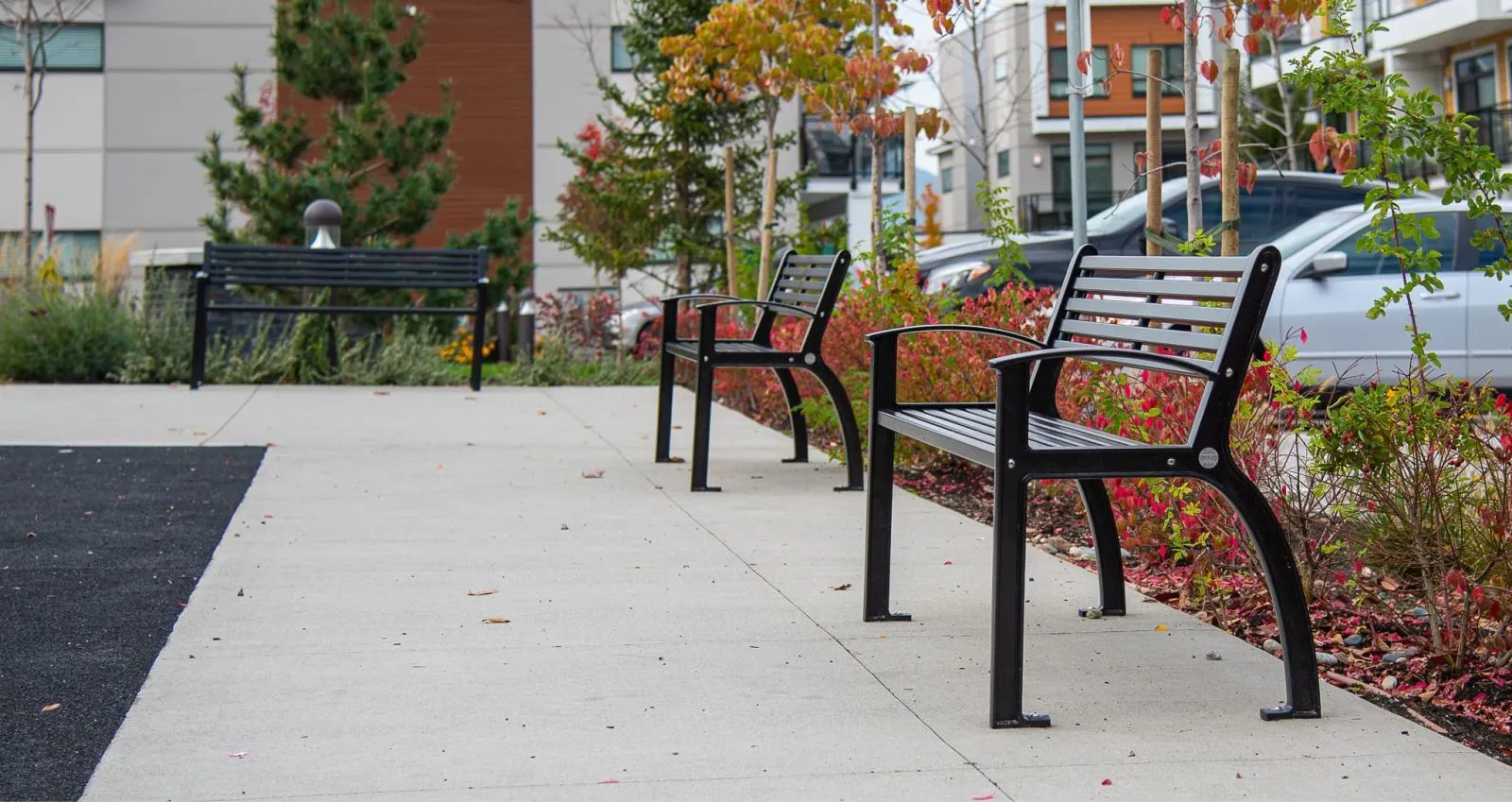 Beselt benches provide seating in an outdoor space with modern buildings and landscaping. The benches feature recycled plastic lumber and black powder-coated frames.