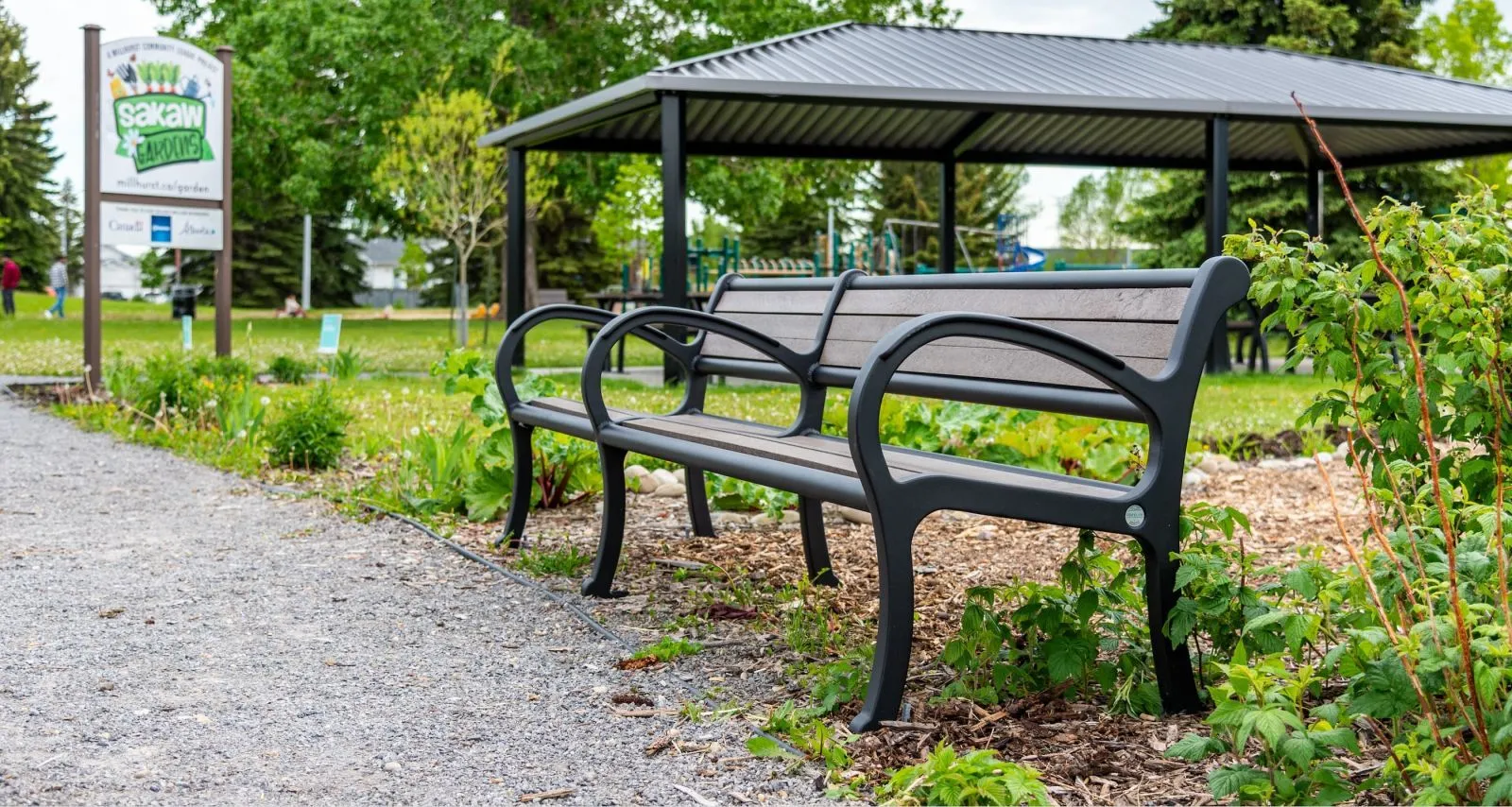 A Mountain Classic bench provides seating in Sakaw Gardens. The bench features recycled plastic lumber and a black powder-coated frame.