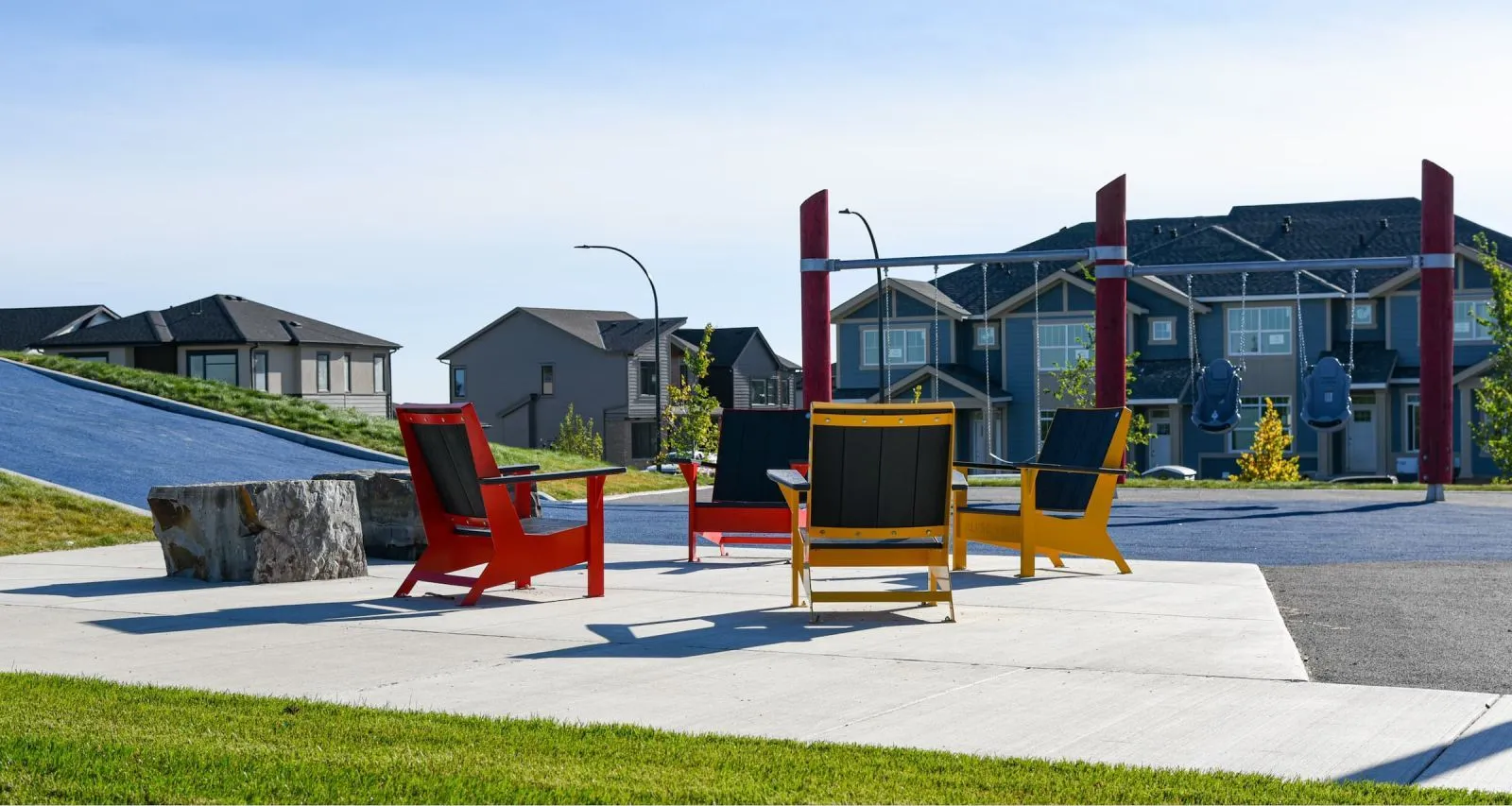 Colorful JEM lounge chairs create a vibrant gathering space in a residential area. The chairs feature recycled plastic lumber and powder-coated metal frames.