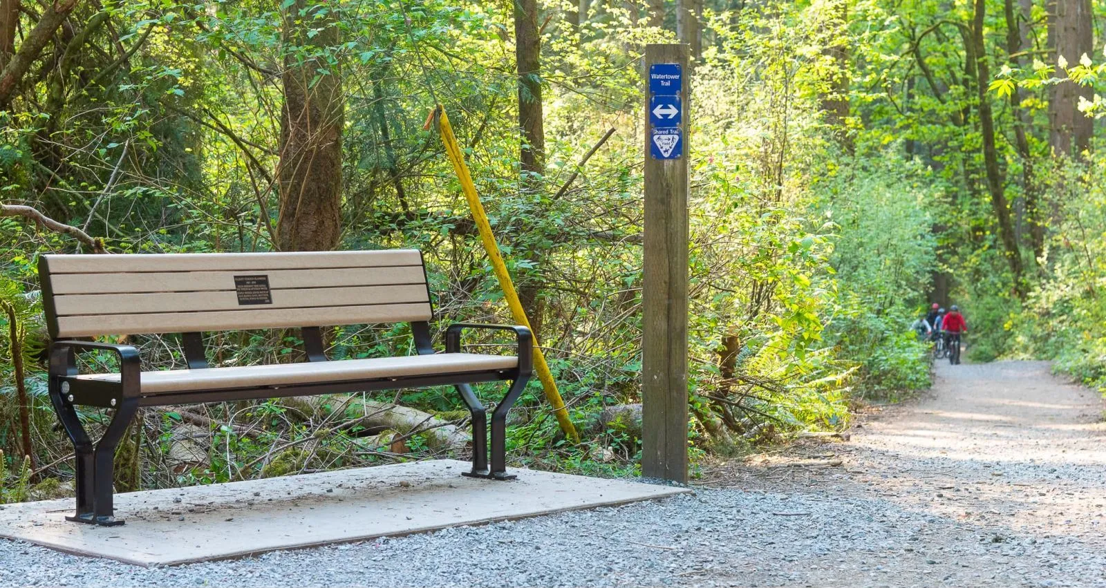 A Koble 6ft memorial bench sits along the Watertower Trail in Watershed Park Reserve, Delta, British Columbia. The bench features recycled plastic lumber and a black powder-coated frame.