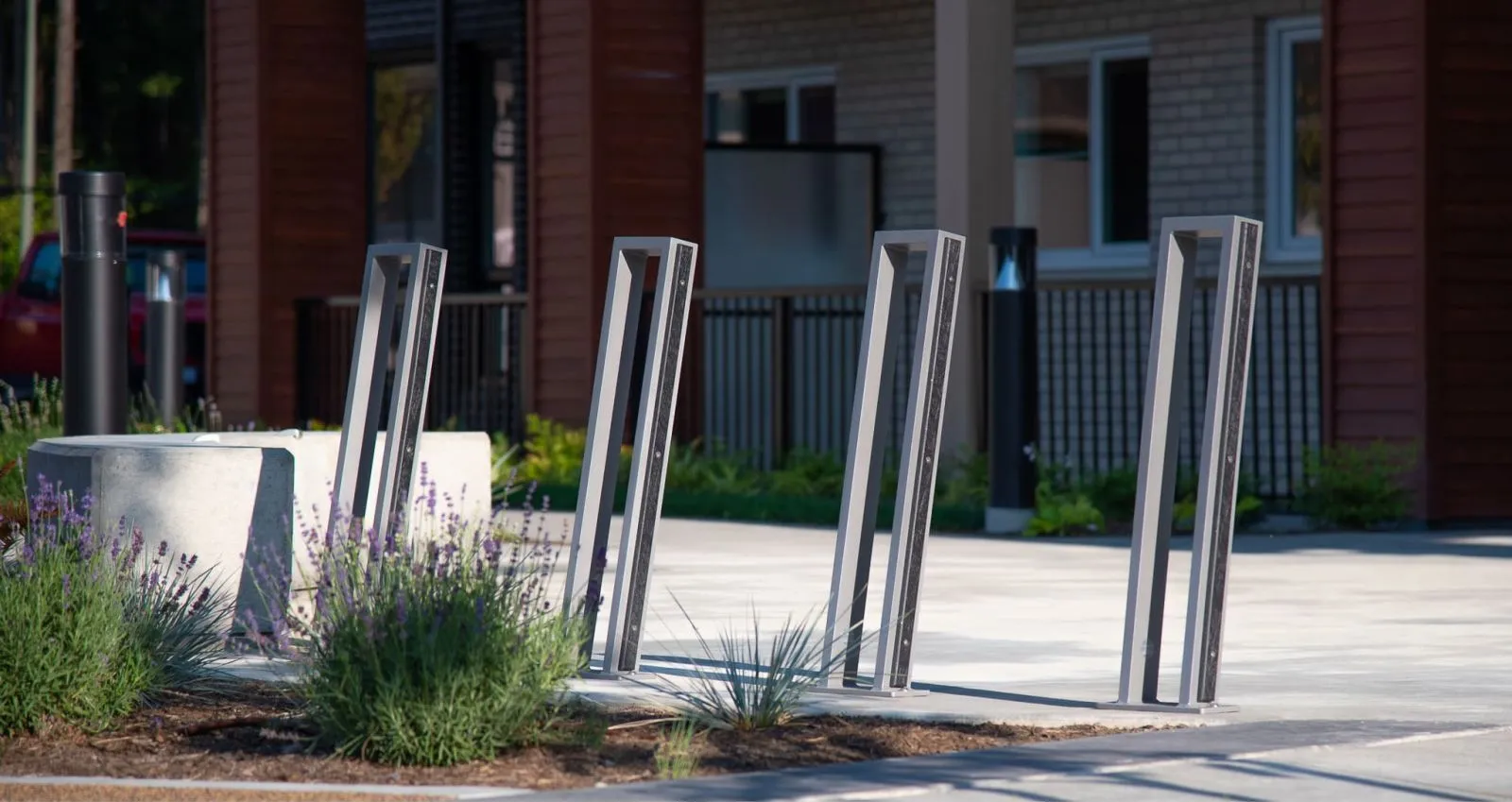 Urban Form 2 Space Bike Racks provide secure bike parking in a modern design. The bike racks are installed on a paved surface with landscaping and building in the background.