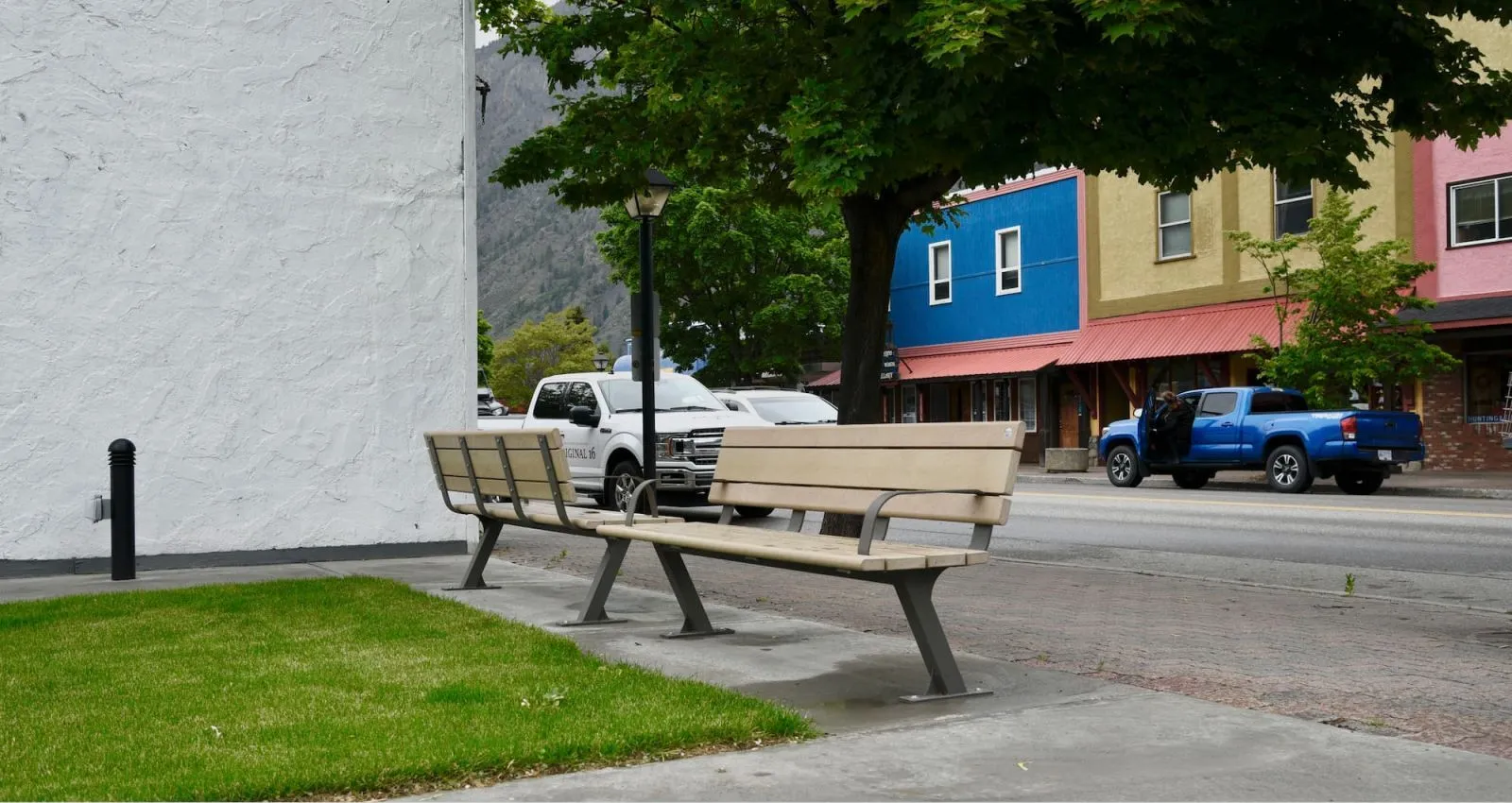 Two Bayview benches line a sidewalk in Keremeos, British Columbia. The benches feature recycled plastic lumber and powder-coated metal frames, providing comfortable seating in a vibrant streetscape.