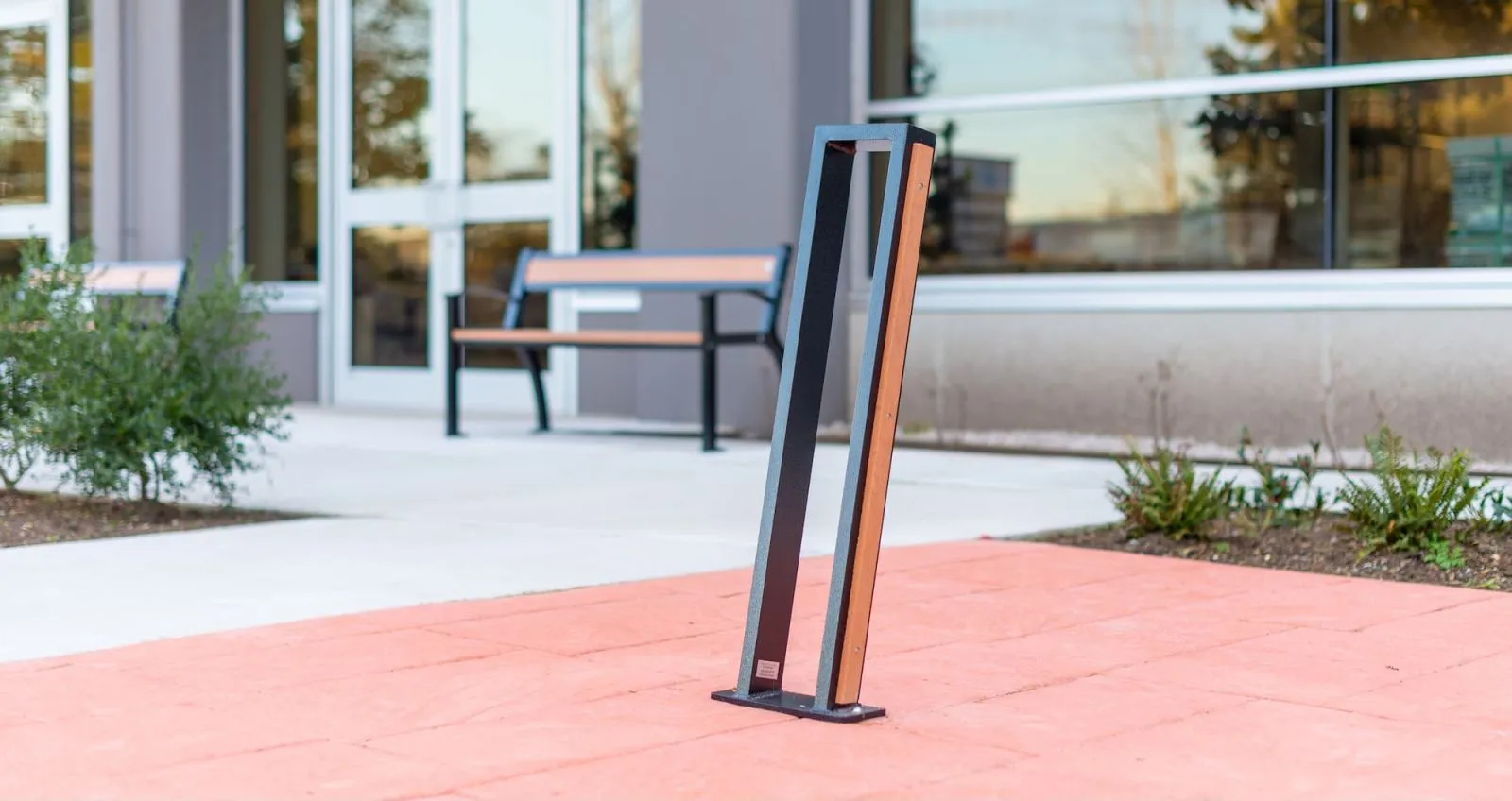 Urban Form 2 Space Bike Rack provides secure bike parking outside a modern building. The rack features recycled plastic lumber accents and a durable powder-coated frame.