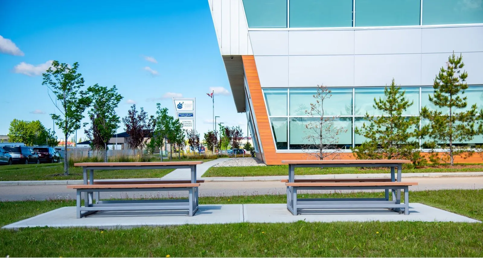 Two heavy-duty picnic tables provide outdoor seating at Elk Island Catholic School in Sherwood Park, Alberta. The tables feature a durable design with recycled plastic lumber tops and powder-coated metal frames.