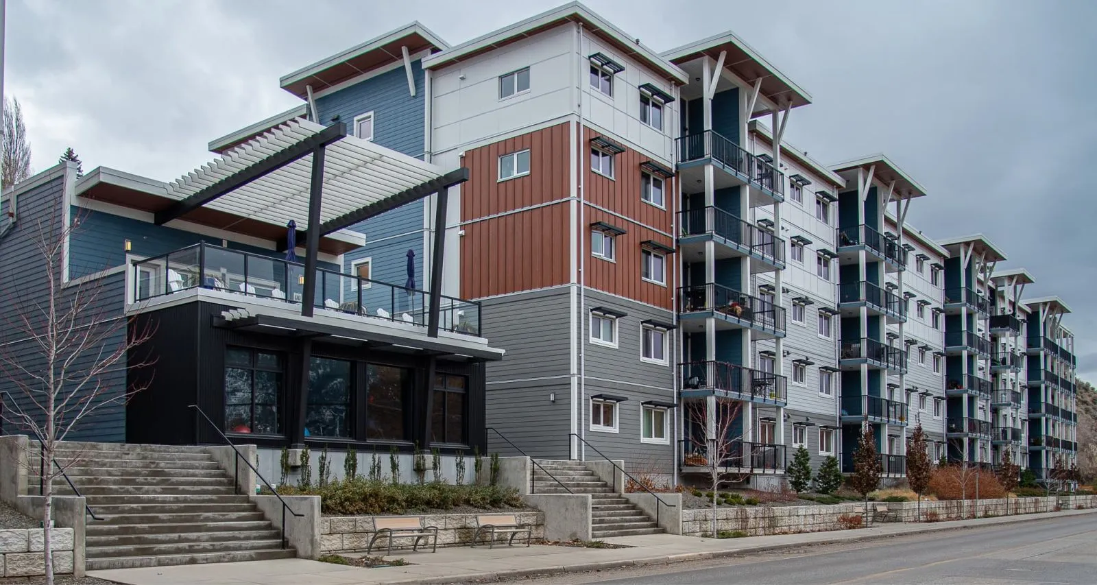 Benches are placed along the steps leading up to a multi-story apartment building. The benches provide seating for residents and visitors.