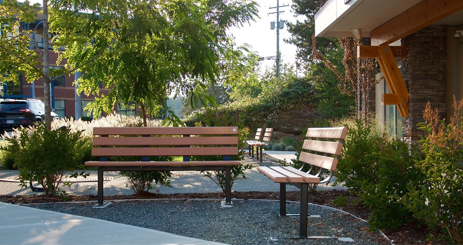 Durable benches provide comfortable seating in a landscaped outdoor space. The recycled plastic lumber and powder-coated metal construction ensures longevity and style.