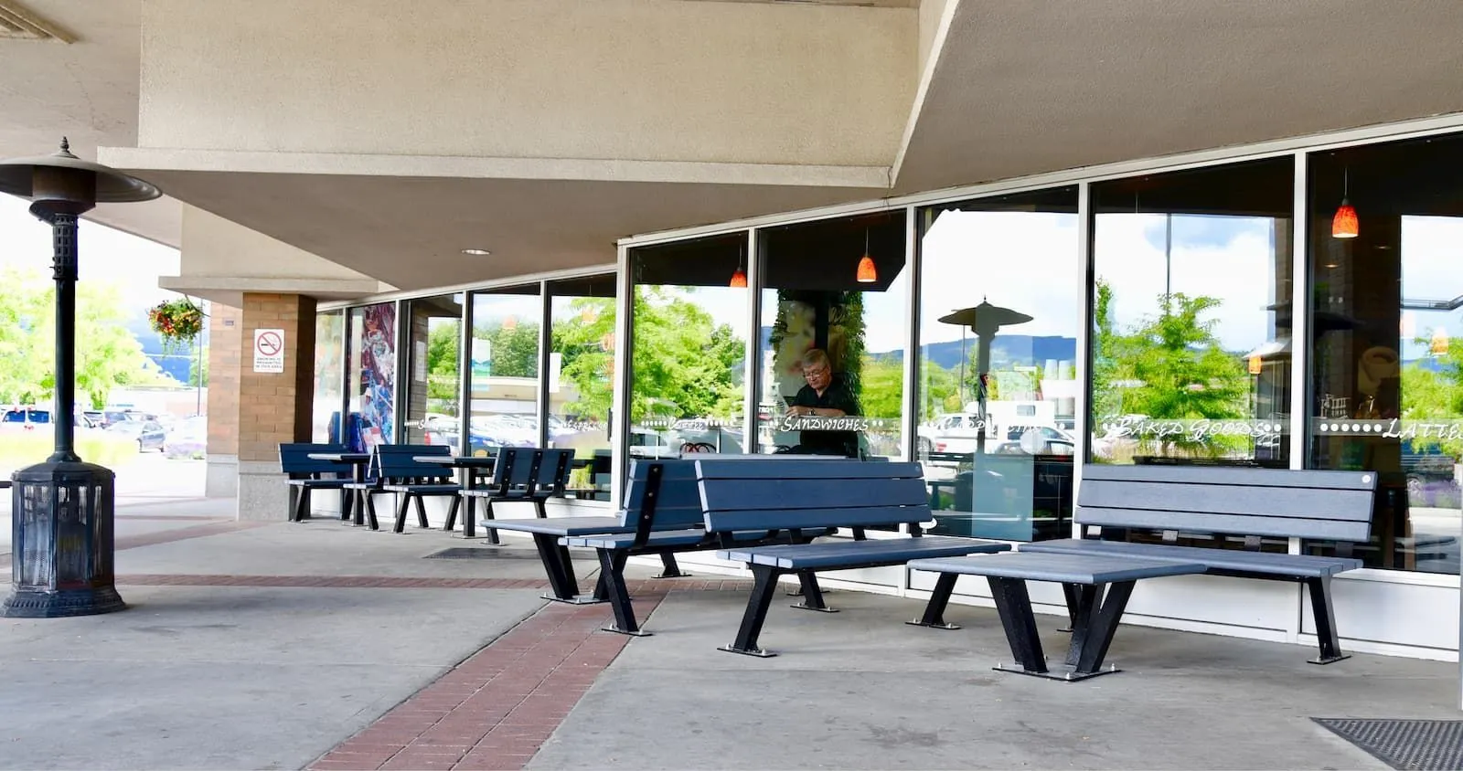 Bayview benches and coffee tables provide outdoor seating at Orchard Plaza in Kelowna, British Columbia. The furniture features recycled plastic lumber and powder-coated metal frames.