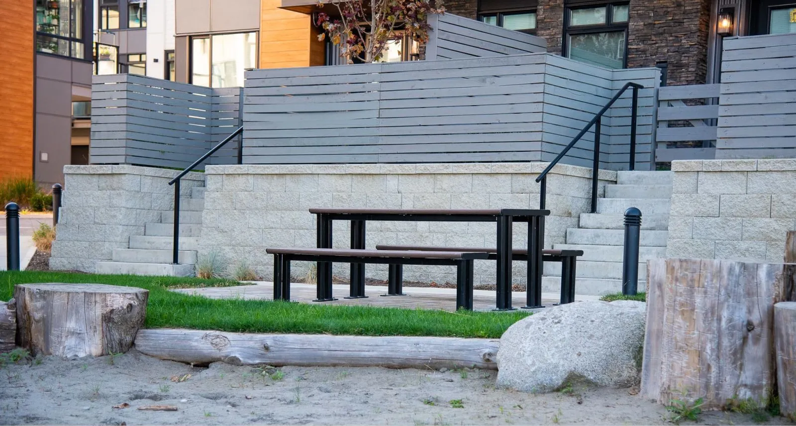 Larson picnic table with recycled plastic lumber top and black powder-coated frame, set in a landscaped outdoor space. The table provides a comfortable and durable seating solution for public areas.
