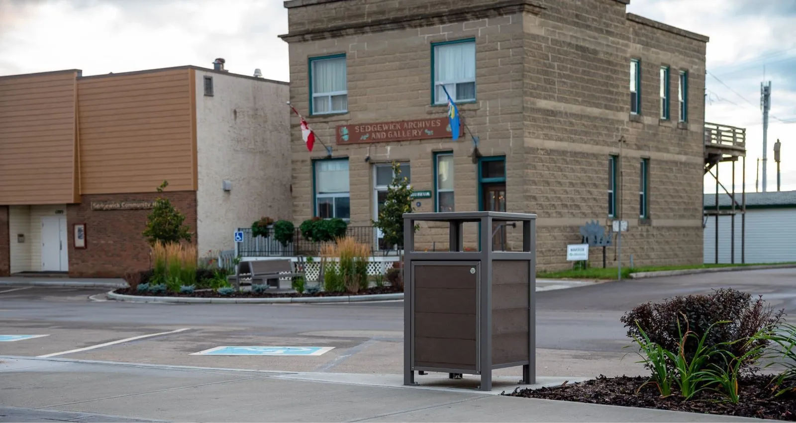 Urban Form Easy Access Waste Receptacle in a public space. The bin features recycled plastic lumber and a powder-coated metal frame.
