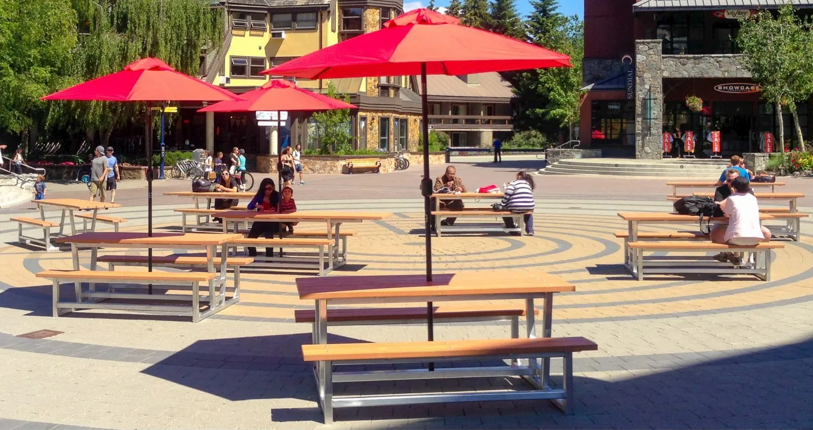 Heavy-duty picnic tables provide outdoor seating in a pedestrian plaza. The tables feature recycled plastic lumber tops and metal frames.