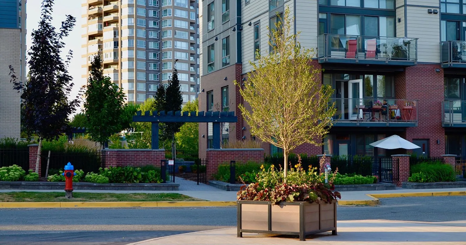A Rutherford planter box adds greenery to the streetscape at Central Park Village in Abbotsford, British Columbia. The planter features recycled plastic lumber and a powder-coated metal frame.