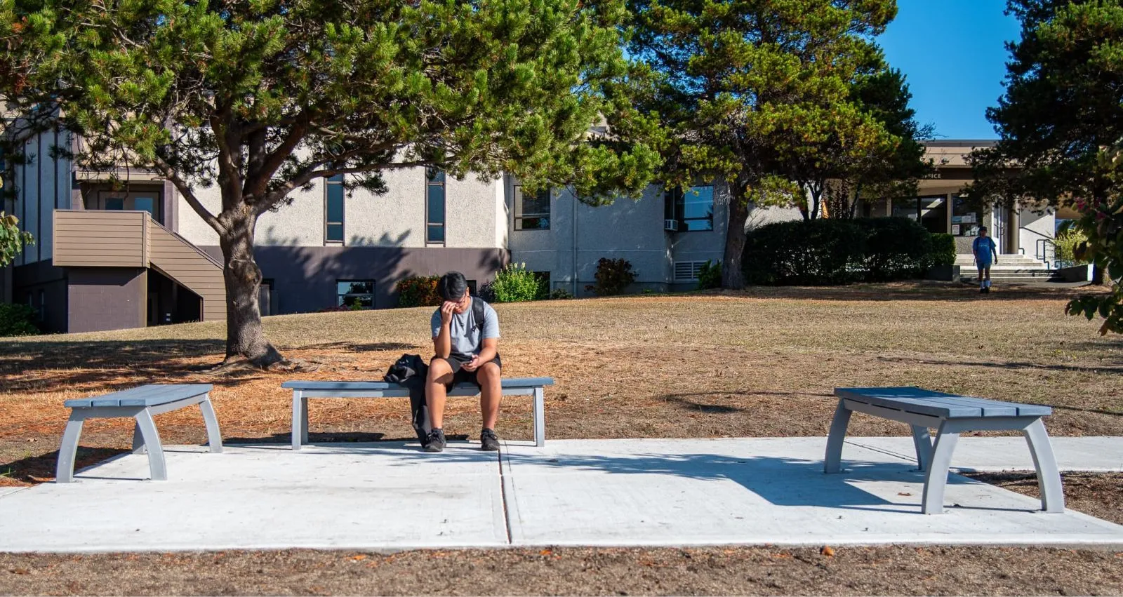 Aylesbury Backless Benches provide seating at Pacific Christian School in Saanich, British Columbia. The benches feature a light gray finish and are placed on a concrete pad in a grassy area.