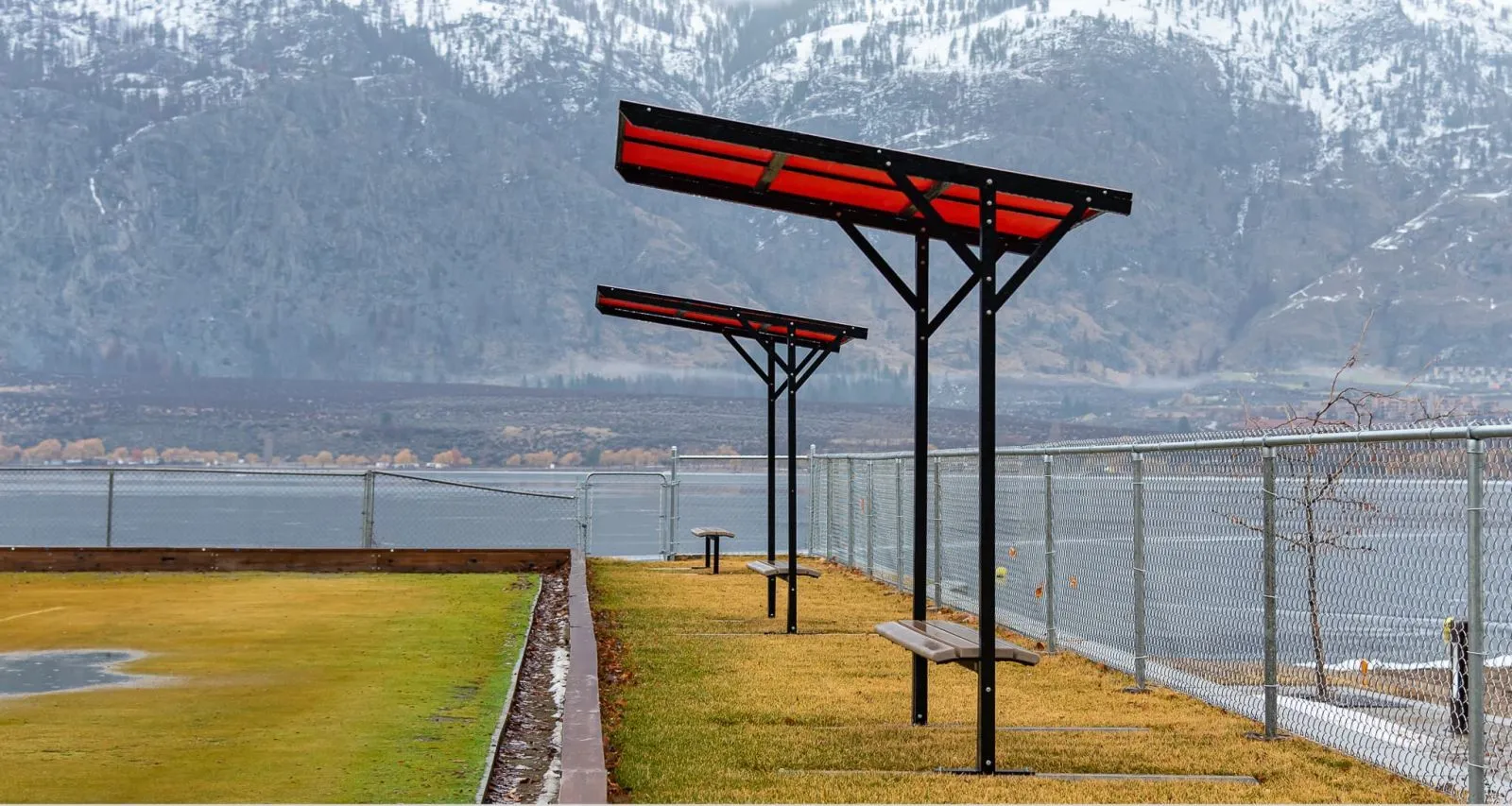 Contoured backless benches with sun shades provide seating at the Lawn Bowling Club in Osoyoos, British Columbia. The benches offer a place to rest with a scenic view of the lake and mountains.