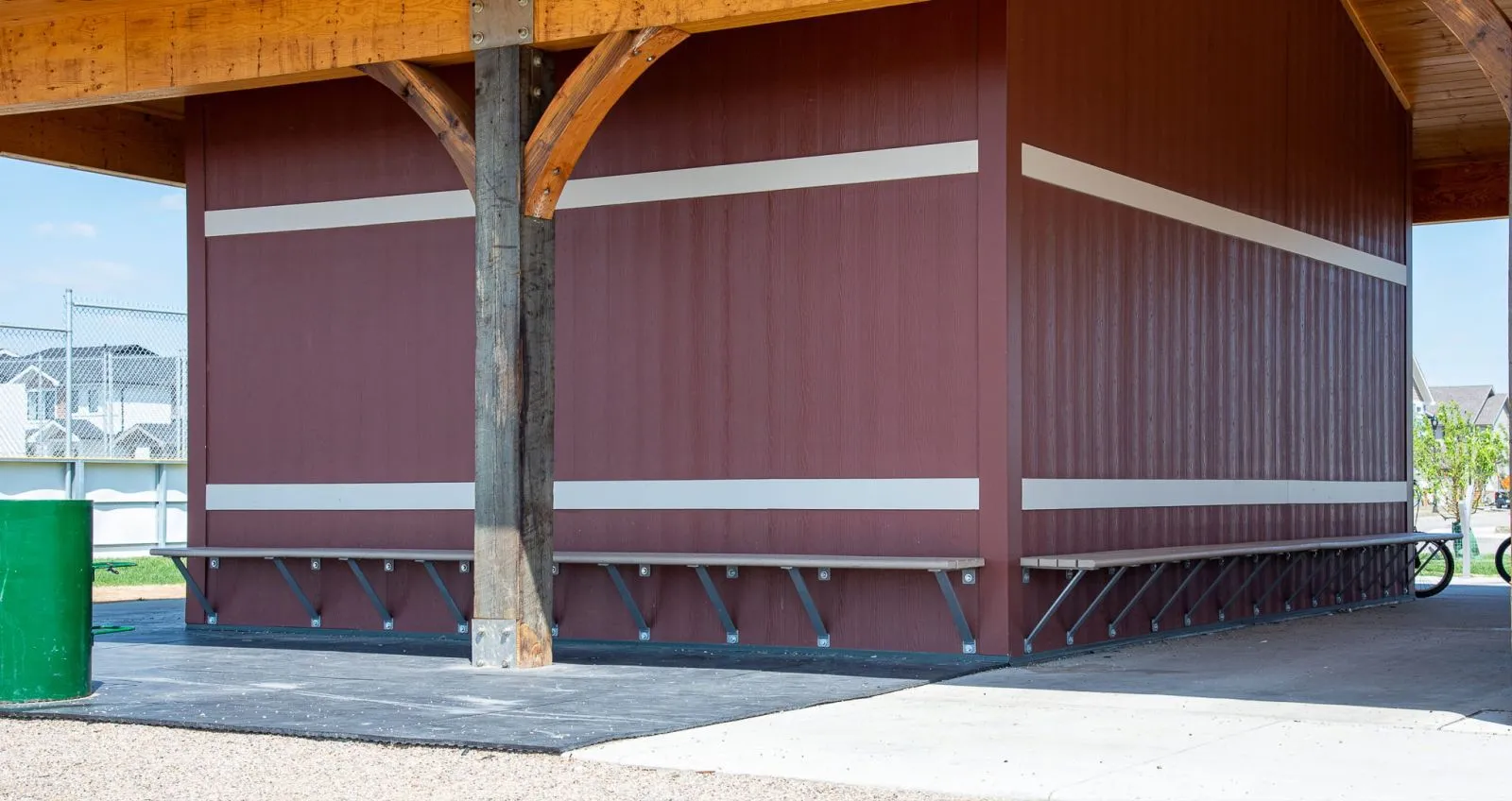 Standard wall-mounted benches provide seating under a covered structure at Horizon Station Park. The benches feature recycled plastic lumber.