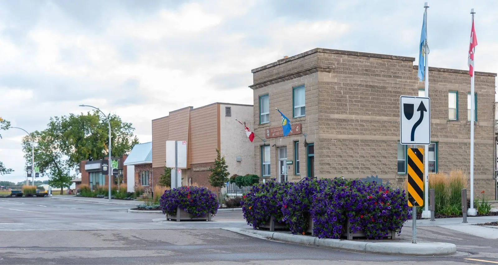Self-watering square planters enhance the streetscape in Sedgewick, Alberta. The planters feature a simple, modern design and are filled with colorful flowers.