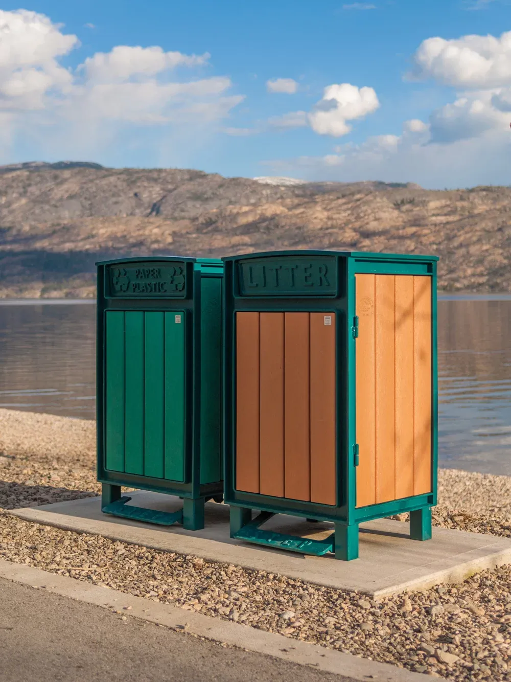Beselt Square Top Waste Receptacles with foot pedals are placed on a concrete pad near a lake. These durable litter bins feature recycled plastic lumber and powder-coated metal frames.