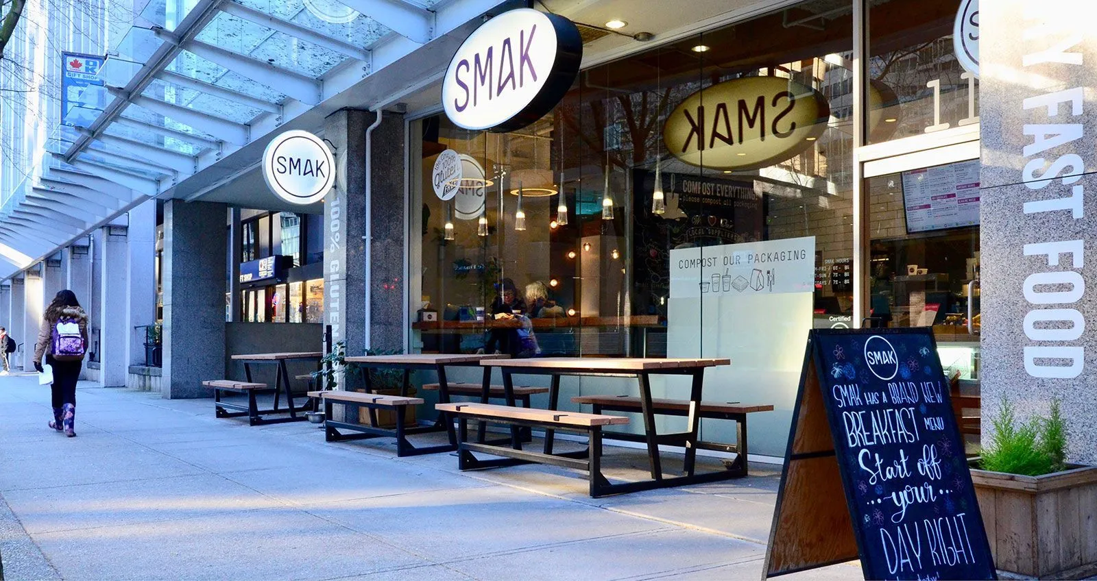 Outdoor picnic tables and benches provide seating outside a restaurant. The tables feature recycled plastic lumber tops and black frames.