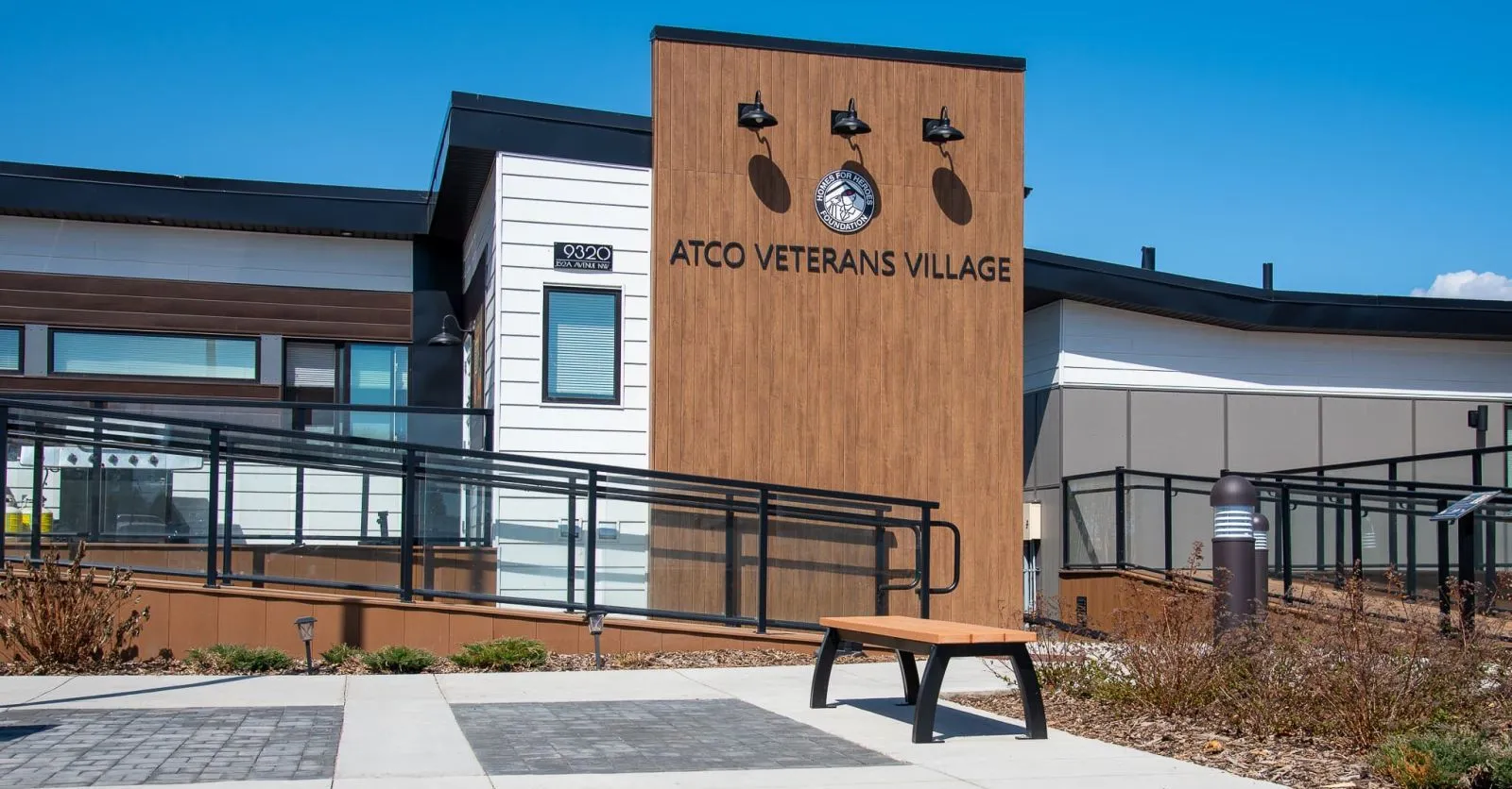 Aylesbury Backless Bench provides seating at the ATCO Veterans Village in Edmonton, Alberta. The bench features recycled plastic lumber and a black powder-coated frame.