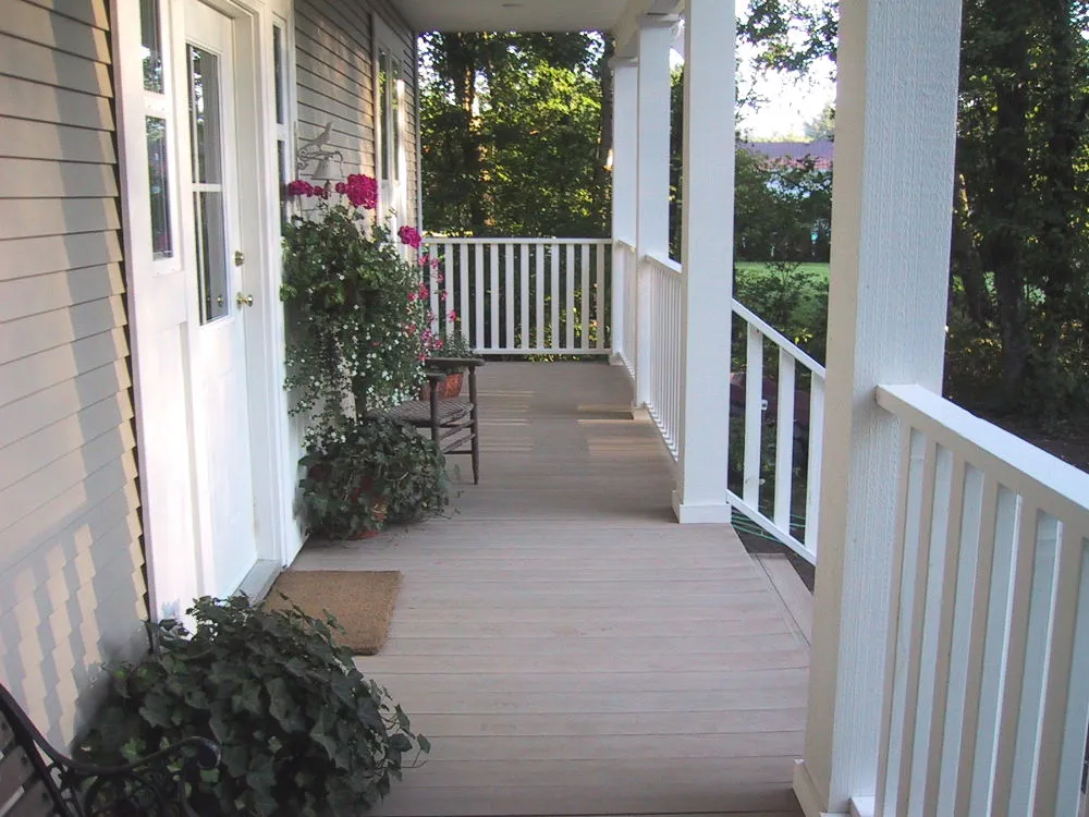 A porch with decking made from recycled plastic lumber. The decking is a light grey color, and the railings and posts are white.