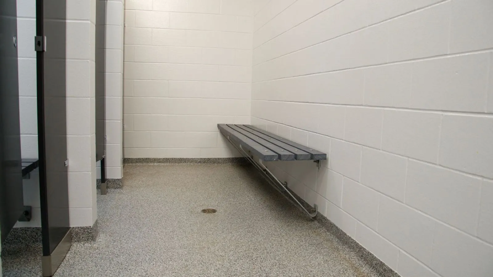 Wall-mounted bench seating in a washroom. The bench features recycled plastic lumber slats and a metal support frame.