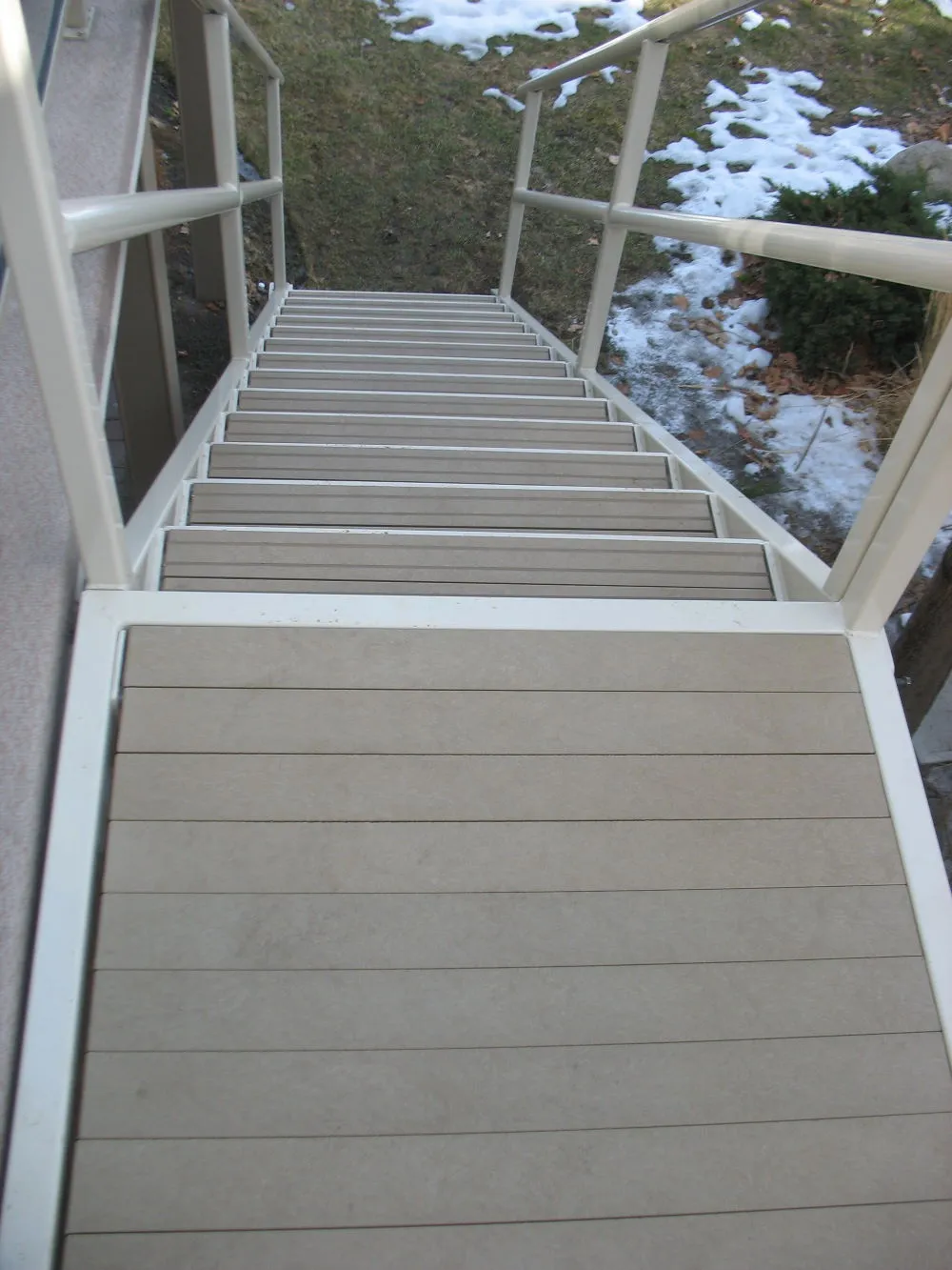 Staircase with recycled plastic lumber steps and white metal railing. The steps are made of durable, low-maintenance material.