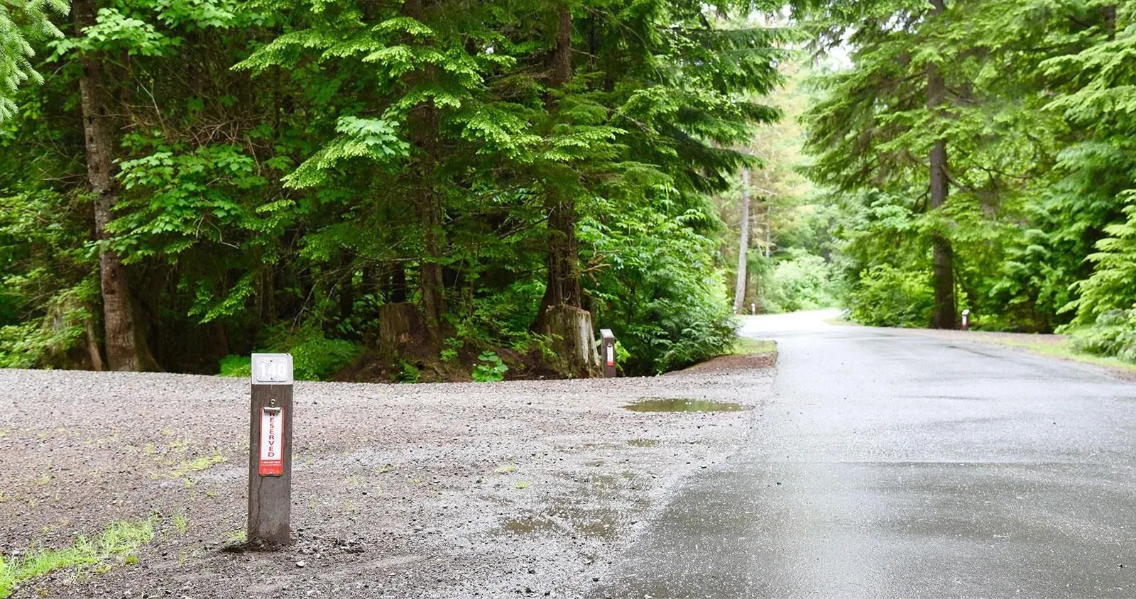 Campsite marker post at Lakelse Provincial Park near Terrace, British Columbia. The post is made of wood and has a reserved sign.