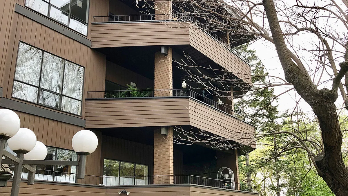 Deck rail top cap application for recycled plastic lumber. The deck features brown horizontal planks and black metal railings.