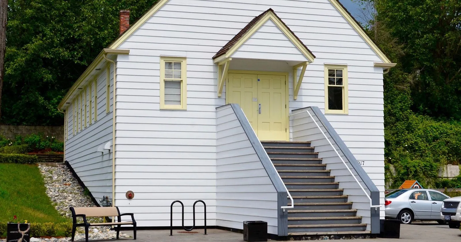 A Classic bench sits outside the Chapel By the Sea Heritage Hall in White Rock, British Columbia. A Surf bike rack is also visible.