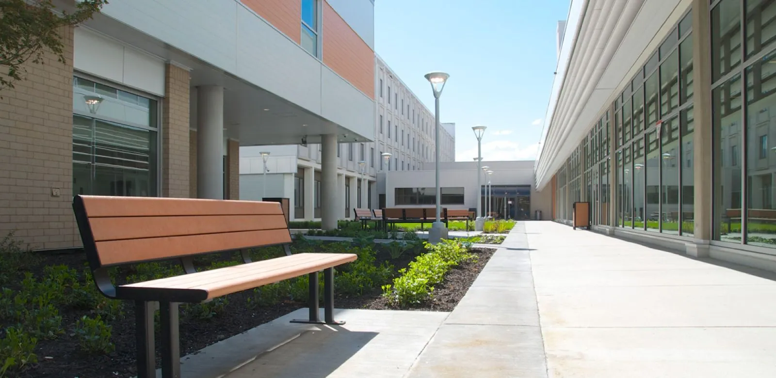 Larson benches provide seating along a walkway at Kelowna General Hospital. The benches feature recycled plastic lumber slats and a powder-coated metal frame.
