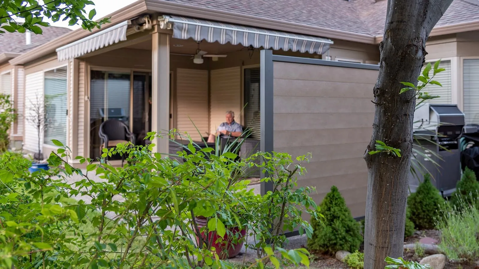 A privacy screen encloses an outdoor patio, providing a secluded space for relaxation. The screen features horizontal planks in a neutral tone, complemented by a dark frame.